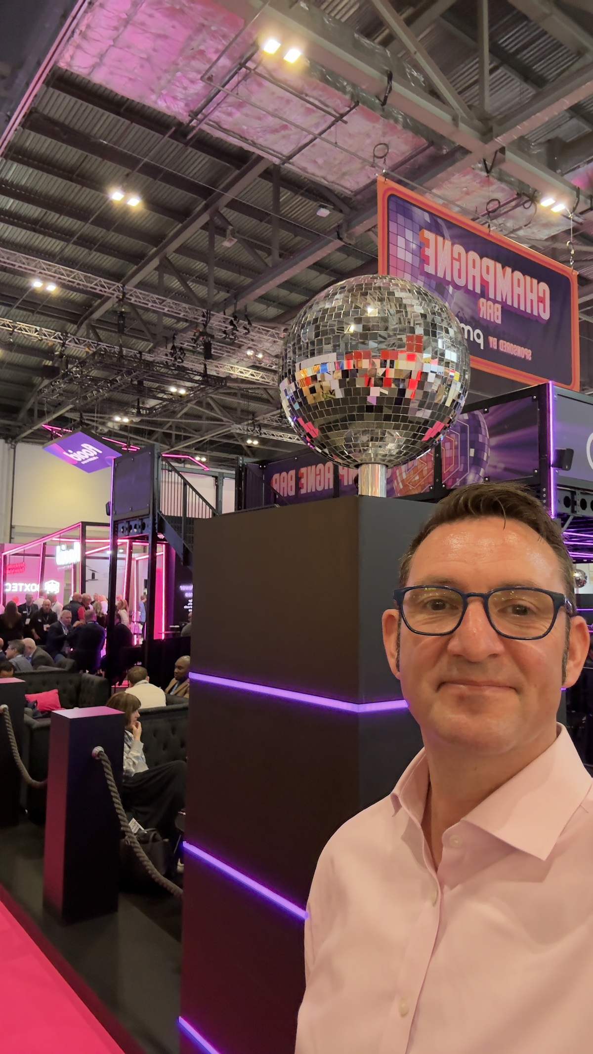 Matthew Gaunt at the Retail Technology Show, in front of the champagne bar and its mirror ball